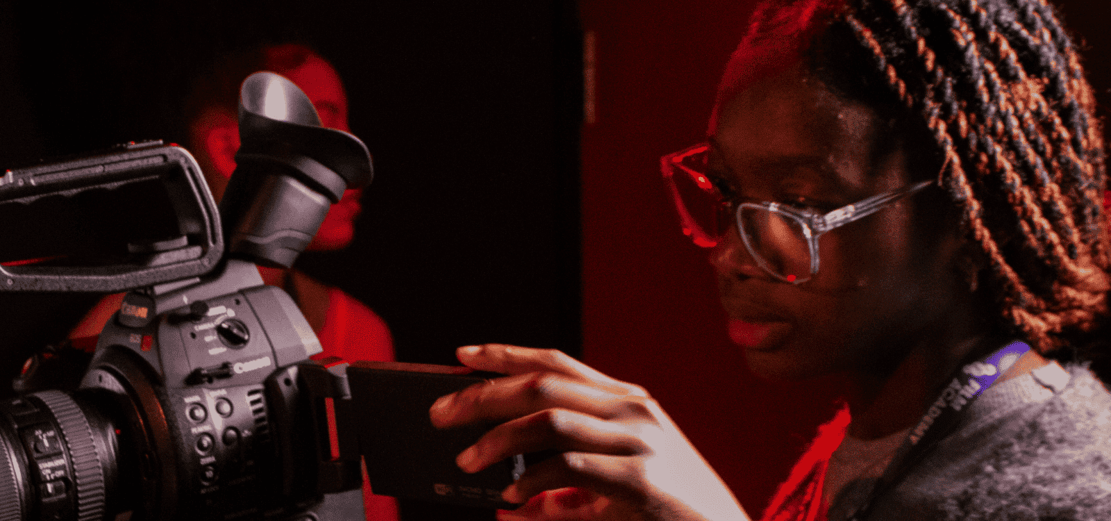 A BFI Film Academy short course student sets up a shot in a darkened room with red back lighting