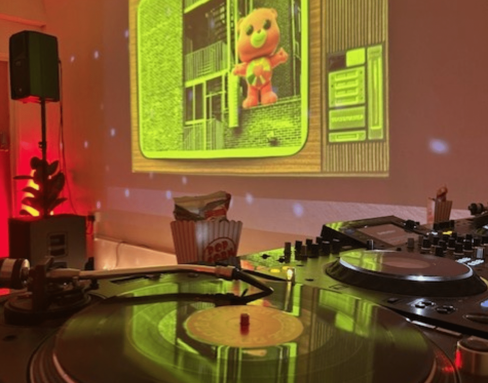 a vinyl record spins in a room with disco lights on a wall there's a projected image of a carebear in an industrial estate
