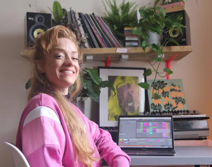 AJA Ireland press image - Aja sitting at a desk with a laptop computer displaying Ableton software