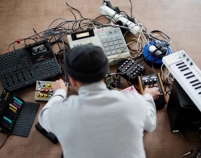 Artist and musician Tom Harris with assortment analogue and digital music production equipment