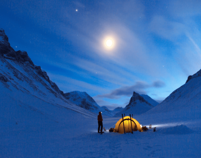 A tent in a snowy, mountainous moonlit landscape