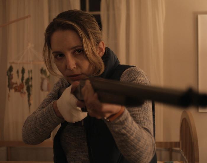 A woman points a shotgun